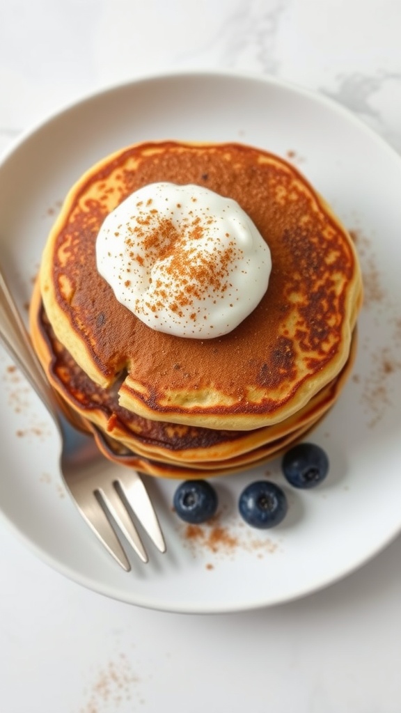 A stack of keto pancakes topped with Greek yogurt and a sprinkle of cinnamon.