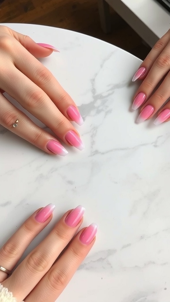 Close-up of hands with ombre pink chrome nails on a marble table.